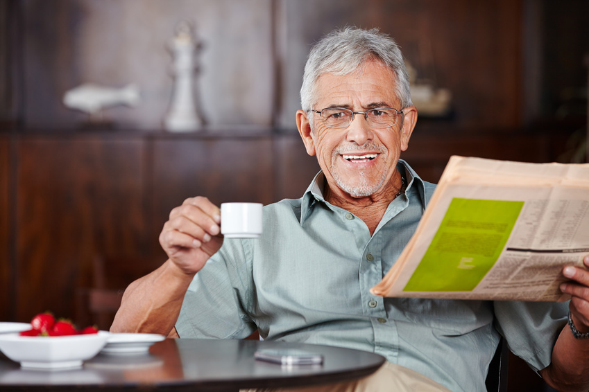 Mann der einen Kaffee trinkt und Zeitung liest